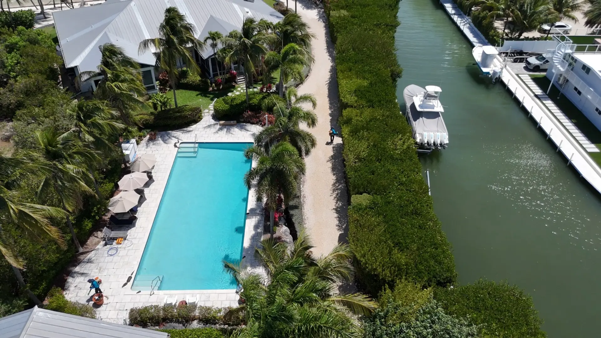 Technician treating the grounds of a waterfront home with pool and dock